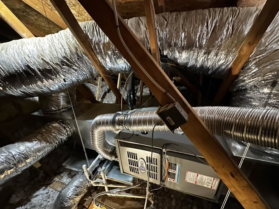 An attic view of an HVAC air handler unit and ductwork installed by Rios Brothers Heating and Cooling LLC in Gilbert, AZ.