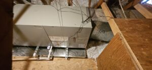 An HVAC furnace unit installed in an attic space with insulation and wooden framing by HoxAir Heating & Cooling in Phoenix, AZ