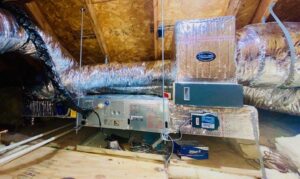An HVAC air handler unit connected to insulated ducts in an attic, installed by Pelican Heating and Air in Carlsbad, CA.