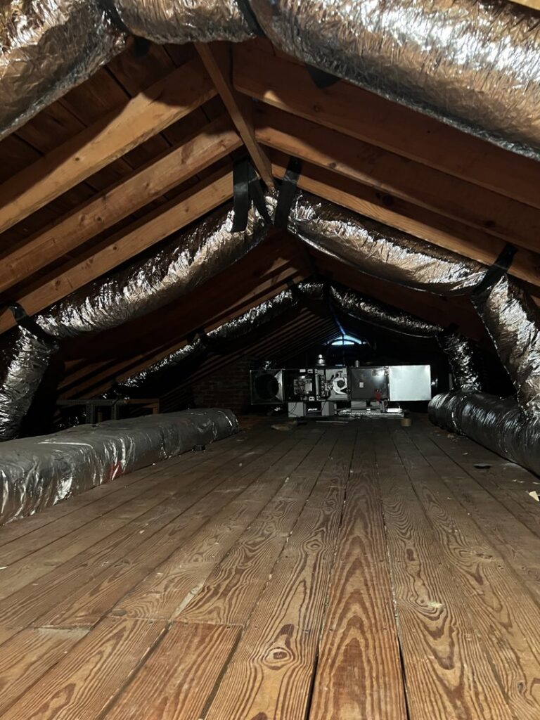 An attic space showing a newly installed HVAC unit and ductwork by Hendrix Heating & Air in Newport News, VA.