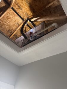 An HVAC unit and ductwork visible through an attic access by Comfort Systems and Solutions in Coventry, RI