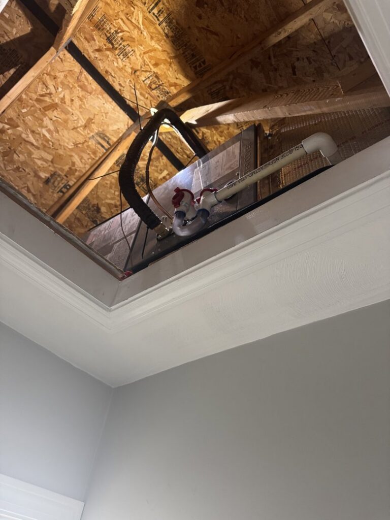 An HVAC unit and ductwork visible through an attic access by Comfort Systems and Solutions in Coventry, RI