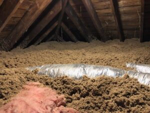 Attic with blown-in insulation and flexible HVAC ductwork installed by HomeWorks Energy in Medford, MA.