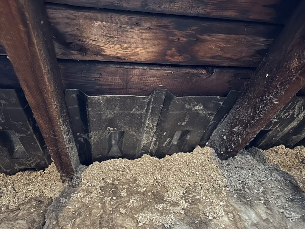 Attic space showing insulation and ventilation baffles installed by HomeWorks Energy in Medford, MA.