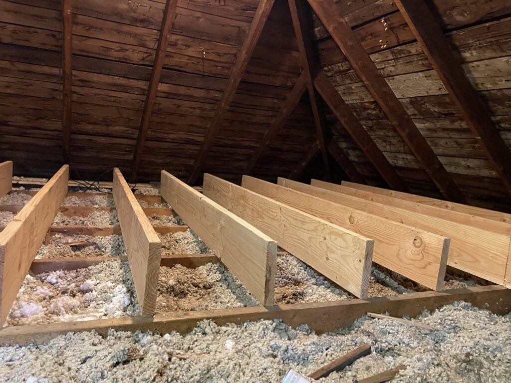 Attic space with new insulation and wooden beams installed by HomeWorks Energy in Medford, MA.