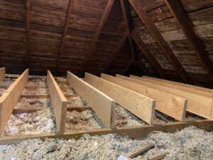 Attic space with new insulation and wooden beams installed by HomeWorks Energy in Medford, MA.