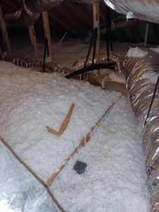 Attic insulation with some debris, indicating a potential area for pest control or remediation services by Eco-Safe Pest Control in Dallas, TX