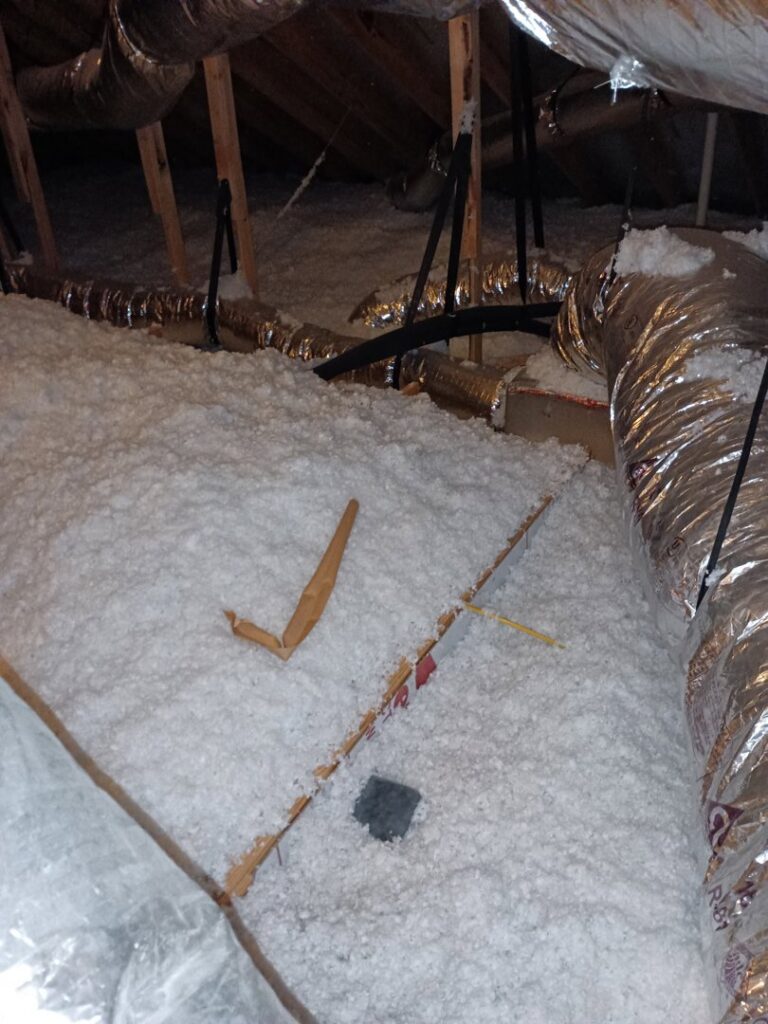 Attic insulation with some debris, indicating a potential area for pest control or remediation services by Eco-Safe Pest Control in Dallas, TX