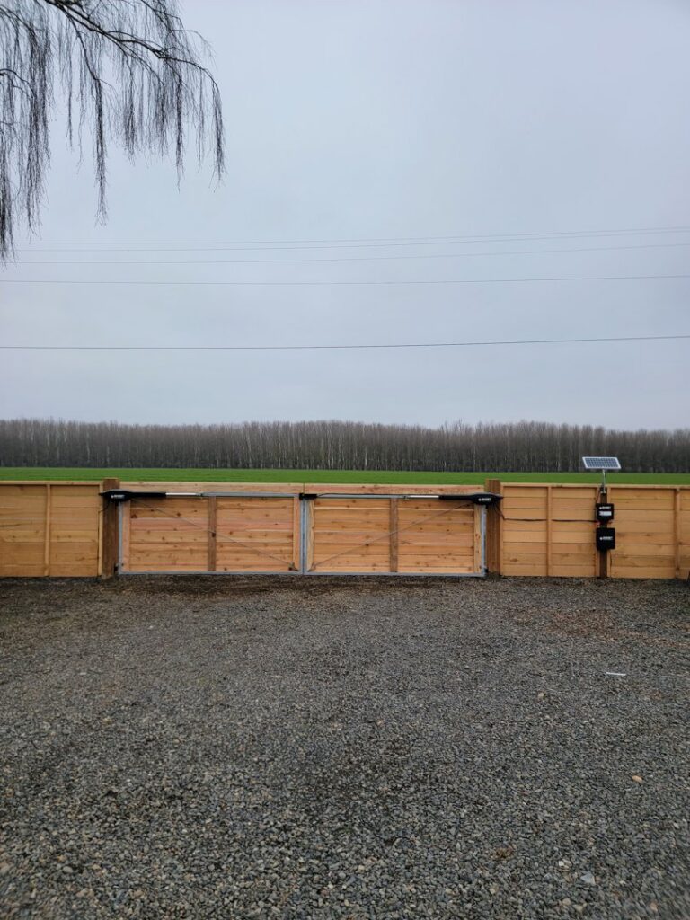 An automated wooden entry gate with a solar panel for power, installed by Faxon Fencing in Corvallis, OR.