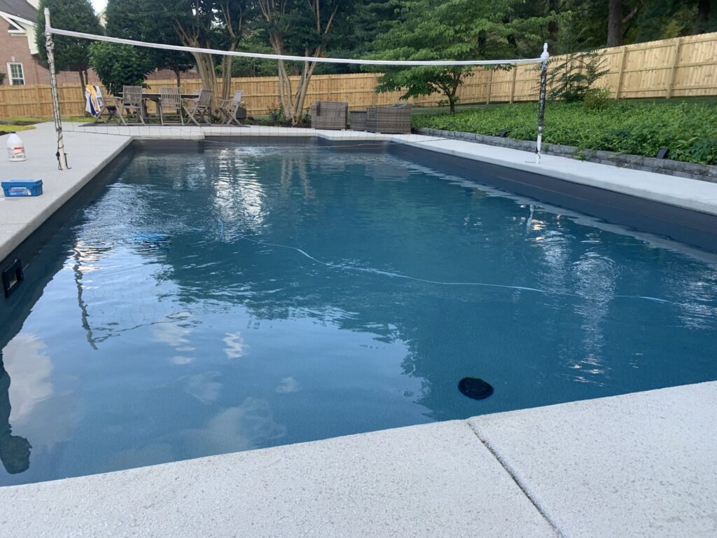 An automatic pool cleaner working in a residential swimming pool with a volleyball net by Aqua Doc Pool And Spa in Franklin, TN.