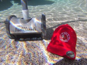 An automatic pool cleaner and a Pool Rescuers LLC hat visible underwater, demonstrating cleaning services in Gilbert, AZ.