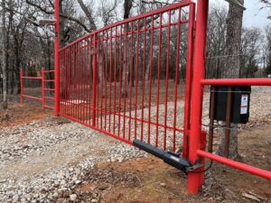 A large automatic red metal entry gate installed by ProScape Outdoor Construction LLC in Norman, OK.