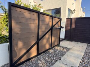 A large automatic sliding gate with brown composite panels and a black metal frame, installed by Harwell Fencing & Gates Inc. in Los Angeles, CA.