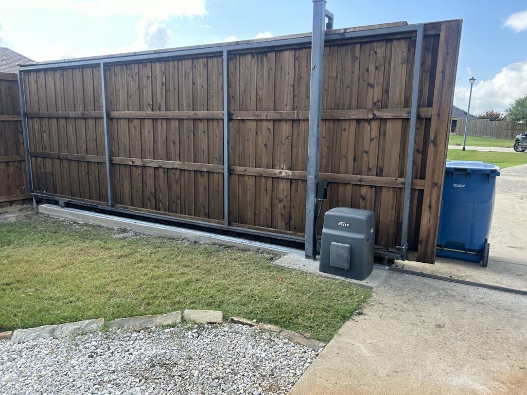 An automatic sliding wood fence and gate system with a visible motor mechanism by Craftsman Automatic Gates in Dallas, TX