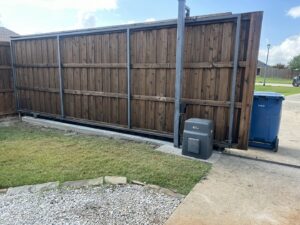 An automatic sliding wood fence and gate system with a visible motor mechanism by Craftsman Automatic Gates in Dallas, TX