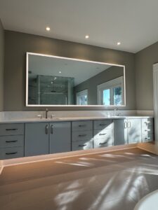 A bathroom vanity with a backlit mirror and under-vanity lighting, installed by Johnson Electric in Port Angeles, WA.