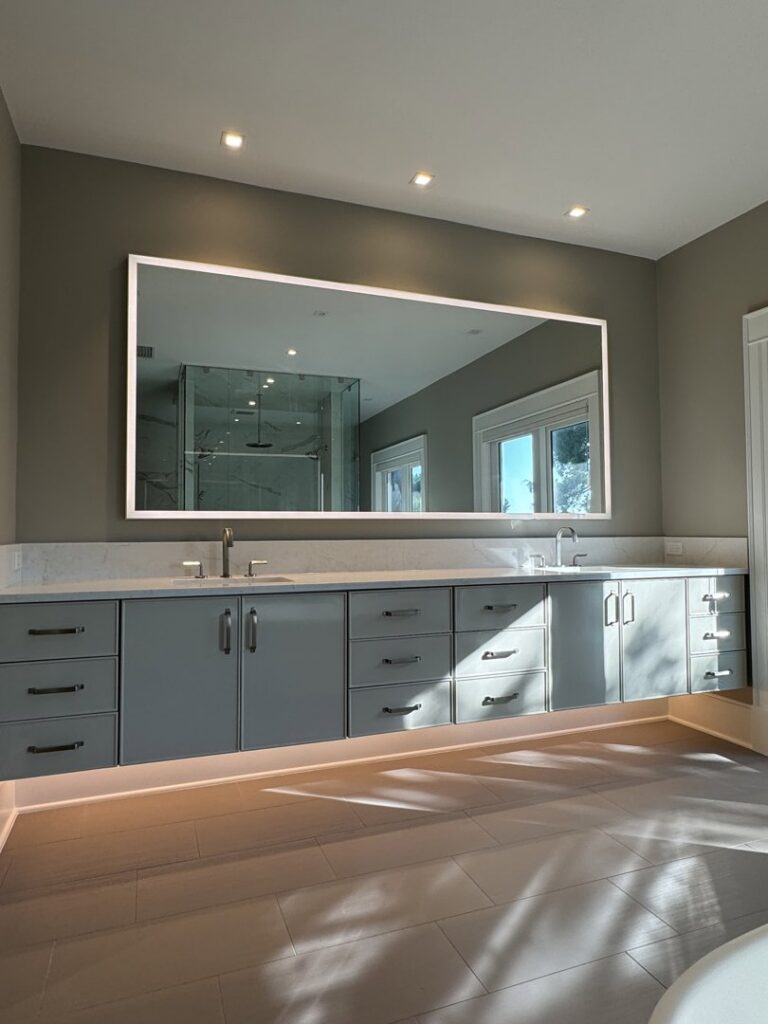 A bathroom vanity with a backlit mirror and under-vanity lighting, installed by Johnson Electric in Port Angeles, WA.