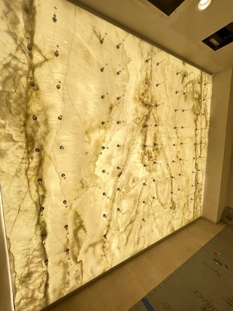 A close-up of a custom backlit onyx wall panel installation by Focal Electric Company in Dallas, TX.