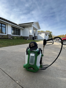 A backpack sprayer with a Metro Pest Solutions hat, ready for pest control service in West Des Moines, IA.