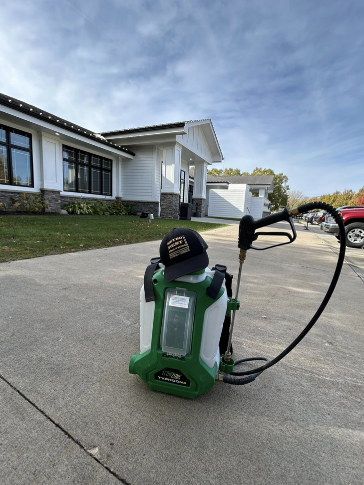 A backpack sprayer with a Metro Pest Solutions hat, ready for pest control service in West Des Moines, IA.