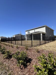 A newly installed black aluminum fence securing a residential backyard by Boost My Home in St. Augustine, FL.