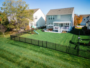 An expansive backyard featuring a black metal fence, deck, and playset installed by Integrous in Gap, PA