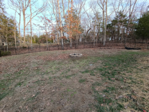 A spacious backyard featuring a black metal fence and a fire pit installed by Fence Experts STL in Fenton, MO