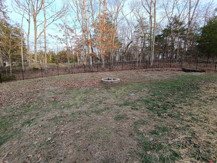 A spacious backyard featuring a black metal fence and a fire pit installed by Fence Experts STL in Fenton, MO
