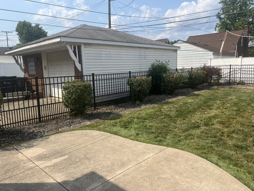 A black metal fence installed in a backyard, bordering a garage, by Final Touch Fencing LLC in Macomb Township, MI.