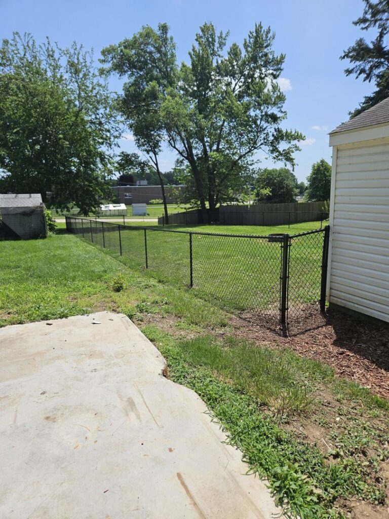 A black chain-link fence installed in a residential backyard by JM Fence Works in Davenport, IA.