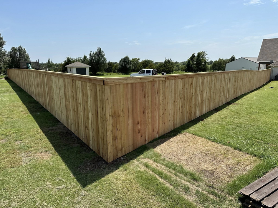 A backyard corner with a newly installed wood fence by DB Construction in Fort Smith, AR.
