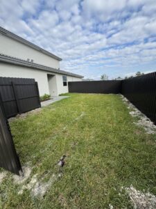 A backyard enclosed by a dark gray scalloped fence with a matching gate by Osuna Ornamental Fences & Gates in Cutler Bay, FL.