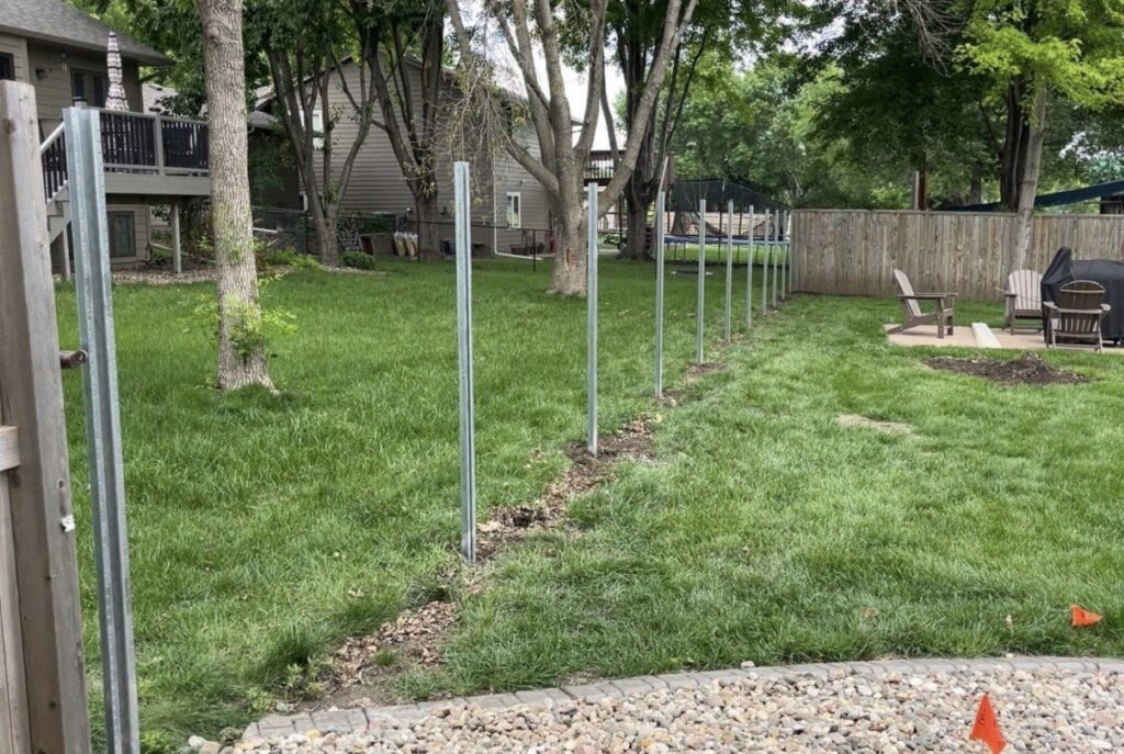 Metal fence posts installed in a residential backyard, ready for fencing by The GateKeeper Perimeter Fence & Automated Security in Sioux Falls, SD