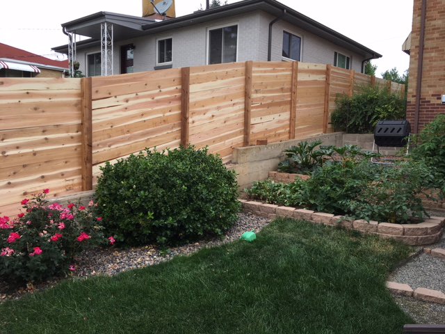 A modern horizontal slat fence bordering a backyard garden, installed by Accent Fence & Design in Lakewood, CO.