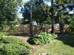 A long, modern horizontal slat wooden fence installed in a lush backyard by Sparta Fencing in Ely, UK.