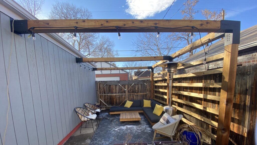 A modern horizontal wood fence providing privacy for a backyard patio with a wooden pergola, installed by Fence Guru LLC in Denver, CO.