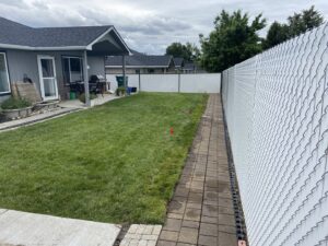 A well-maintained backyard lawn with a paved pathway, showing professional care by McLain Lawn & Landscape in Spokane, WA.
