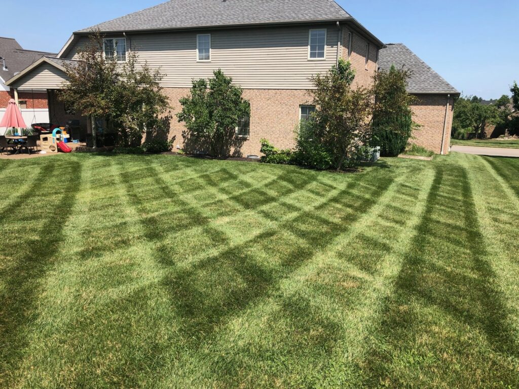 A backyard lawn showcasing a precise crisscross mowing pattern by C&R Lawn Care and Property Services in Evansville, IN.