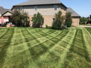A backyard lawn showcasing a precise crisscross mowing pattern by C&R Lawn Care and Property Services in Evansville, IN.
