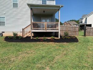A backyard with a deck and newly mulched flower beds by Cutting Edge Lawn Services in Islip, NY