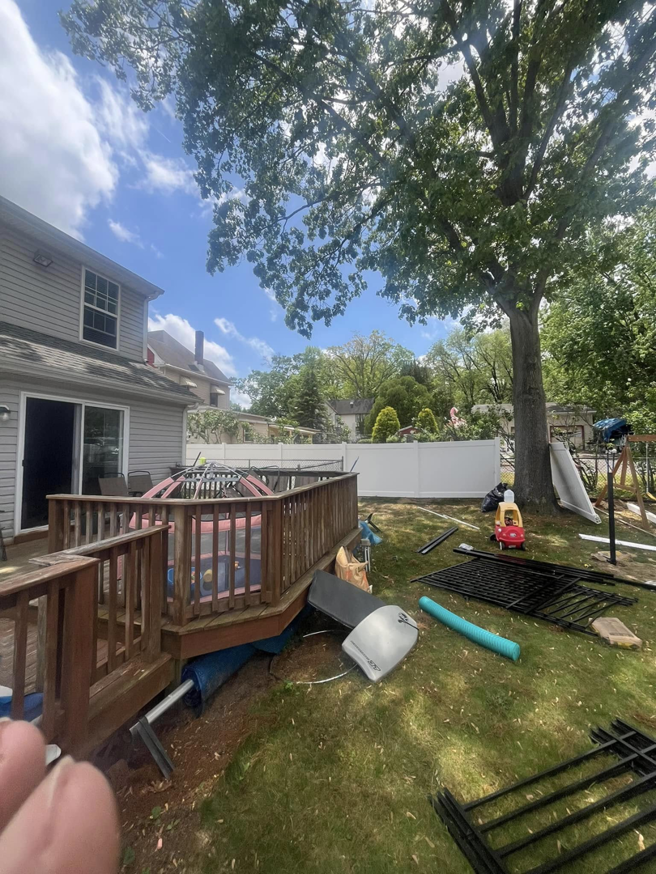 A backyard with a partially installed white vinyl fence and black metal panels by Fence Pros LLC in Medford, OR.
