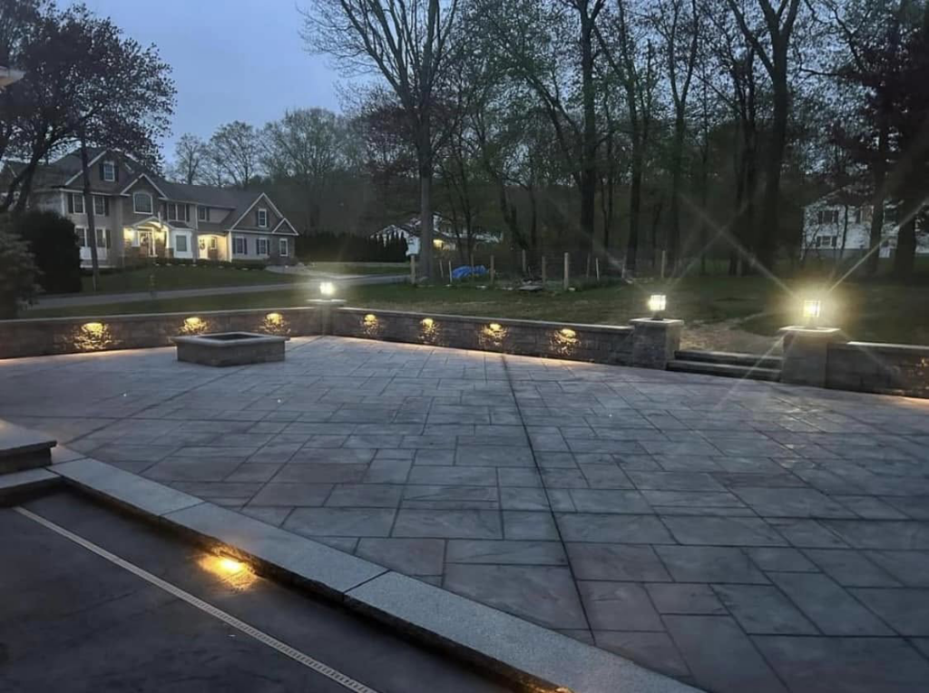 Beautiful backyard patio lighting design by TD Electric in Waterbury, CT, showcasing illuminated walls and pathways.