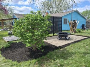 A newly installed backyard paver patio with a fire pit and fresh mulch by VKDYS Lawn Care in Fort Wayne, IN.