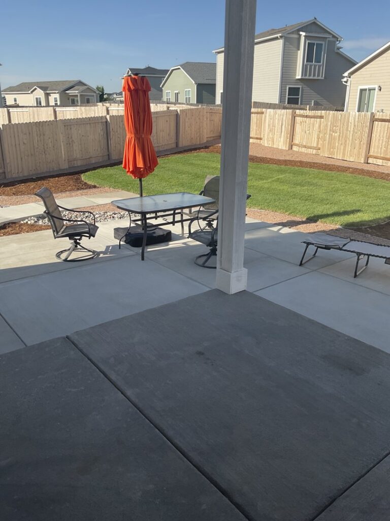 A backyard patio area complemented by a healthy green lawn by The Fisherman Landscaping LLC in Westminster, CO.