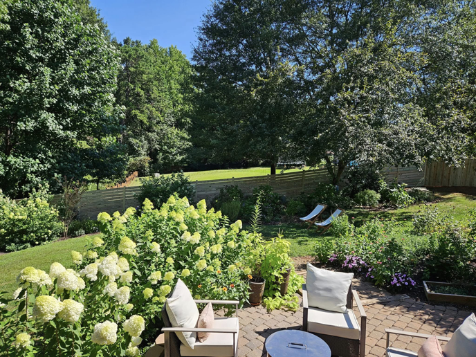 A beautiful backyard patio area with a newly installed horizontal wood fence in the background by The Fence Guy One in Greenville, SC.