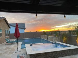 A beautiful backyard pool and spa illuminated at sunset by Blue Magic Pools and More Inc. in Gilbert, AZ.