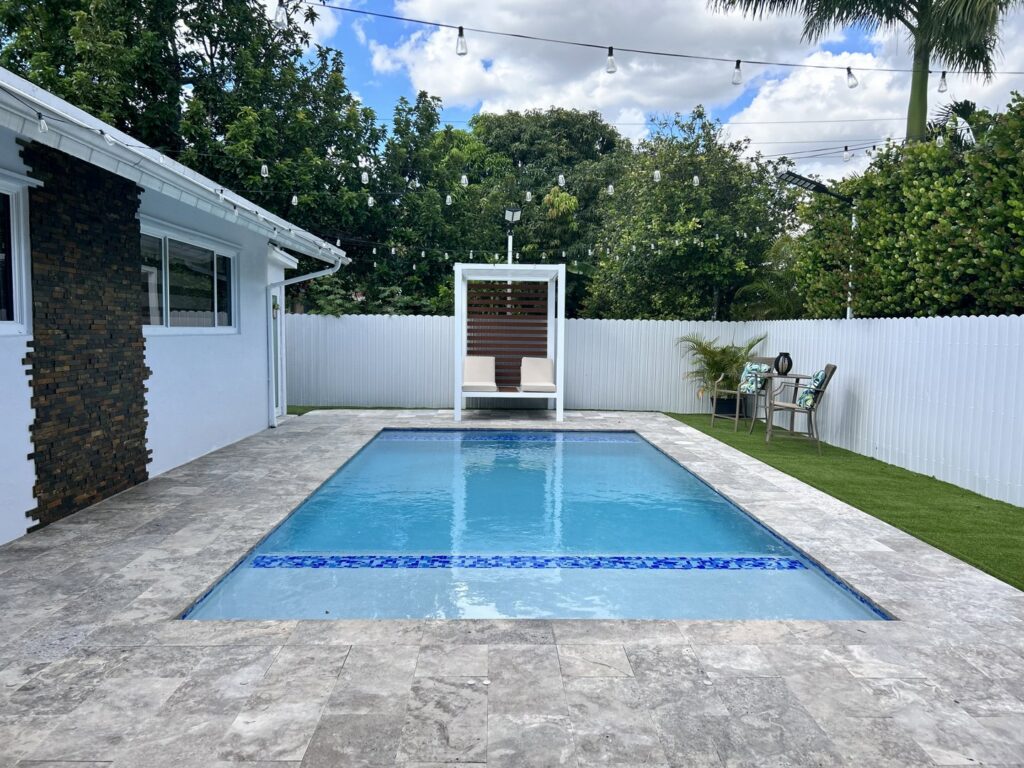 A backyard pool area enclosed by a white scalloped fence installed by Osuna Ornamental Fences & Gates in Cutler Bay, FL.