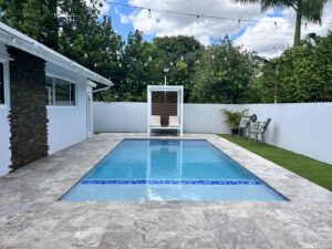 A backyard pool area enclosed by a white scalloped fence installed by Osuna Ornamental Fences & Gates in Cutler Bay, FL.