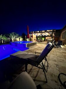 A backyard swimming pool illuminated with blue lighting at night by Blue Magic Pools and More Inc. in Gilbert, AZ.