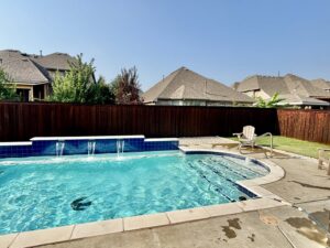 A backyard with a swimming pool and a dark stained privacy fence by Texas Tuff Stain and Seal in Fort Worth, TX.